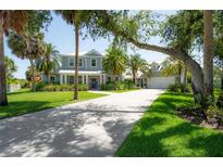 Stunning two-story home with a lush green lawn, palm trees, and a long driveway at 8927 Key West Island Way, Riverview, FL 33578