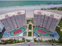 Stunning aerial view of beachfront condo buildings with private tennis courts and beautifully landscaped grounds at 1340 Gulf Blvd # 16A, Clearwater Beach, FL 33767