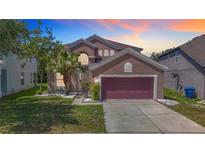 Charming two-story home featuring a well-manicured lawn, a two-car garage and mature landscaping at 14137 Wake Robin Dr, Brooksville, FL 34604