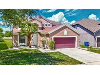 Charming two-story home featuring a landscaped front yard, palm tree, and a brick-paved driveway leading to a two-car garage at 14137 Wake Robin Dr, Brooksville, FL 34604