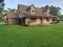 Charming two-story home featuring a brick facade, dormer windows, and a well-manicured lawn at 2615 Southern Oaks Pl, Plant City, FL 33566