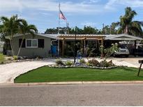 Charming single-story home with tropical landscaping, an American flag, and a white shell driveway at 2912 Case Ave, Bradenton, FL 34207