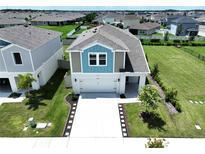 Two-story home boasts a well-maintained lawn, pristine driveway, and a charming blue and gray exterior at 34056 Scarlet Sage Ct, Wesley Chapel, FL 33545