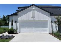 A white, two-car garage with an immaculate driveway is found on the exterior of this modern home at 3719 Nandina Cir, Sun City Center, FL 33573