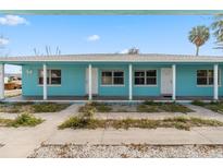 Charming turquoise home with a covered porch and white support columns, offering a relaxed, coastal living vibe at 410 73Rd Ave, St Pete Beach, FL 33706