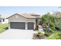 Beautiful home exterior with a tile roof, paver driveway, two car garage, and professional landscaping at 4888 Sevilla Shores Dr, Wimauma, FL 33598