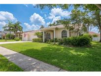 Charming single-story home with well-maintained landscaping and a spacious front yard on a sunny day at 627 Belted Kingfisher N Dr, Palm Harbor, FL 34683