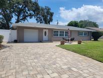 Charming single-story home with a paver driveway, attached garage, and a manicured lawn at 13725 Bermuda Dr, Seminole, FL 33776