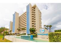 Stunning view of the Ocean Sands building with meticulous landscaping and beautiful water features in the foreground at 14950 Gulf Blvd # 603, Madeira Beach, FL 33708