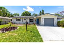 Charming home featuring an inviting front yard with a well-maintained lawn and landscaped garden beds at 1809 Elmwood Dr, Oldsmar, FL 34677
