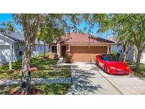 Charming single-story home with a well-manicured lawn, two-car garage and a red sports car parked in the driveway at 18107 Canal Pointe St, Tampa, FL 33647