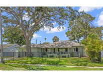 Charming single-story home featuring a manicured lawn, mature shade trees, and a secure black metal fence at 1827 Oregon Ne Ave, St Petersburg, FL 33703