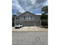 Three-story townhouse with gray facade, balconies, and attached garages; white car parked in front at 27653 Pleasure Ride Loop, Wesley Chapel, FL 33544