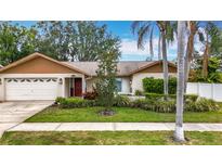 Charming single-story home features a well-manicured front yard with lush landscaping and a two-car garage at 3093 Hillside Ln, Safety Harbor, FL 34695