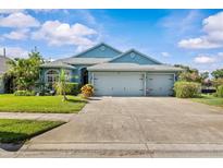 Charming single-story home with a well-manicured lawn, mature trees, and a three-car garage at 378 Wood Chuck Ave, Tarpon Springs, FL 34689