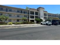 Multi-story condo building featuring balconies, parking, and tropical landscaping, with address number prominently displayed at 861 Maple Ct # 104, Dunedin, FL 34698