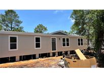 New single-story home featuring a neutral exterior, white-trimmed windows, and a front door, set against a bright blue sky at 10040 Lake Dr, Weeki Wachee, FL 34613