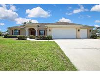 Beautifully landscaped single-story home with a three car garage and a well-manicured front lawn at 12012 Cromwell Way, Spring Hill, FL 34609