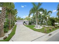 Charming single-story home with tropical landscaping and a spacious driveway leading to an attached garage at 1210 Bay Palm Blvd, Indian Rocks Beach, FL 33785
