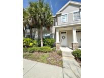 Charming townhome with manicured landscaping and inviting front entrance, enhanced by elegant stone accents and palm trees at 12334 Country White Cir, Tampa, FL 33635