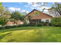 Charming home featuring lush landscaping, a well-manicured lawn, and a unique wood exterior at 1799 Dixie Hwy, Tarpon Springs, FL 34689