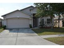Two-story house with a beige exterior, attached two-car garage, and well-maintained lawn at 30742 Birdhouse Dr, Wesley Chapel, FL 33545