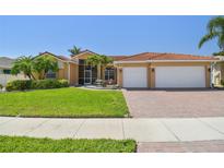 Charming single-story home with a red tile roof, lush landscaping, and a two-car garage at 3737 Gaviota Dr, Sun City Center, FL 33573