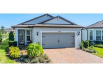 Attractive home featuring a brick driveway, a gray two-car garage door, and manicured landscaping at 5090 Caravel Pt, Land O Lakes, FL 34638
