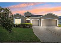 Inviting one-story home featuring a three-car garage, well-maintained lawn, and attractive curb appeal at 6547 Castle Green Pl, Zephyrhills, FL 33541