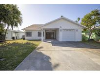 Charming single-story home with a well-maintained lawn, attached garage, and covered entrance at 811 Bay Point Dr, Madeira Beach, FL 33708