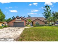 Charming single-story brick home with a well-manicured lawn and two-car garage, nestled under a blue sky with scattered clouds at 9202 Jena Rd, Spring Hill, FL 34608