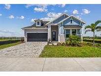 Charming two-story home with blue accents, landscaped yard, and brick paved driveway at 1599 Running Tide Pl, Sarasota, FL 34240