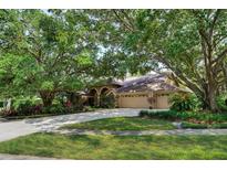 Charming single-story home featuring mature trees, lush landscaping, and a spacious driveway leading to a three-car garage at 17321 Oak Ledge Dr, Lutz, FL 33549