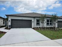 Charming single-story home with a gray garage door, landscaped yard, and a concrete driveway at 2026 Sidney St, Clearwater, FL 33763