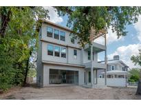 Unfinished three-story home with a garage, porch, and wooden pergola frame under a cloudy blue sky at 2301 N Ridgewood Ave, Tampa, FL 33602