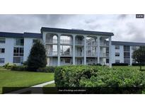 Condo building with balconies, green lawns and shrubbery on a cloudy day at 4801 Airport Rd # 210, Zephyrhills, FL 33542