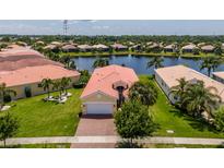 Waterfront home with a red tile roof, beautiful landscaping, and a spacious lawn at 4821 Grand Banks Dr, Wimauma, FL 33598