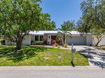 Charming single story home with a metal roof, lush landscaping, and an attached two car garage at 1503 Albemarle Ct, Dunedin, FL 34698