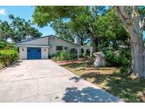 Single story home with a blue garage door, concrete driveway, and lush landscaping at 1514 Florida Ave, Palm Harbor, FL 34683