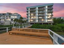 Condos with multiple balconies sit near a boardwalk with a bench at sunset at 19925 Gulf Blvd # 105, Indian Shores, FL 33785