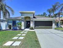 Charming single-story home with a well-manicured lawn, palm trees, and a two-car garage at 6205 Chapel Pines Blvd, Wesley Chapel, FL 33545