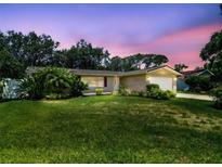 Charming single-story home featuring a well-manicured lawn, lush landscaping, and a warm, inviting curb appeal at 734 Lake Forest Rd, Clearwater, FL 33765
