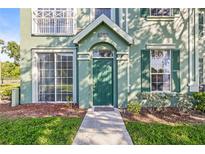 Inviting front entrance with green door, lush landscaping, and well-maintained walkway leading up to the home at 9416 Lake Chase Island Way # 9416, Tampa, FL 33626
