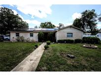 Charming single-story home featuring solar panels, a well-maintained lawn, and a welcoming walkway at 11411 N 19Th St, Tampa, FL 33612