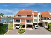 Coastal condo building featuring covered parking, balconies, and waterfront access at 128 1St Street E. # 102, Tierra Verde, FL 33715