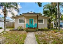 Charming home featuring a vibrant blue front door and two blue chairs on the front porch at 1420 W Rambla St, Tampa, FL 33612
