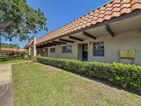 Inviting exterior of home featuring a red tile roof, well-maintained lawn, and established landscaping at 1701 Pinehurst Rd # 16C, Dunedin, FL 34698