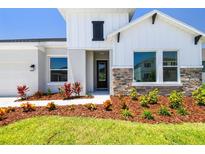 Charming home featuring stone accents, complemented by colorful landscaping and a well-maintained lawn at 6126 Hidden Branch Dr, Apollo Beach, FL 33572
