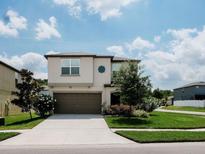 Charming two-story home with a well-manicured lawn and a two-car garage on a sunny day at 6444 Bar S Bar Trl, Zephyrhills, FL 33541