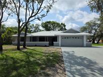 Charming single-story home with a well-manicured lawn, grey exterior, and an attached two-car garage at 7278 Radcliff St, Spring Hill, FL 34606